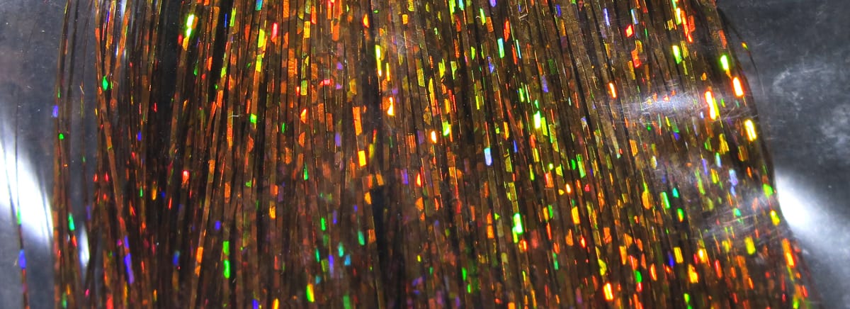 Hedron holographic Flashabou strands in brown with thin metallic fibers reflecting rainbow flashes for fly tying