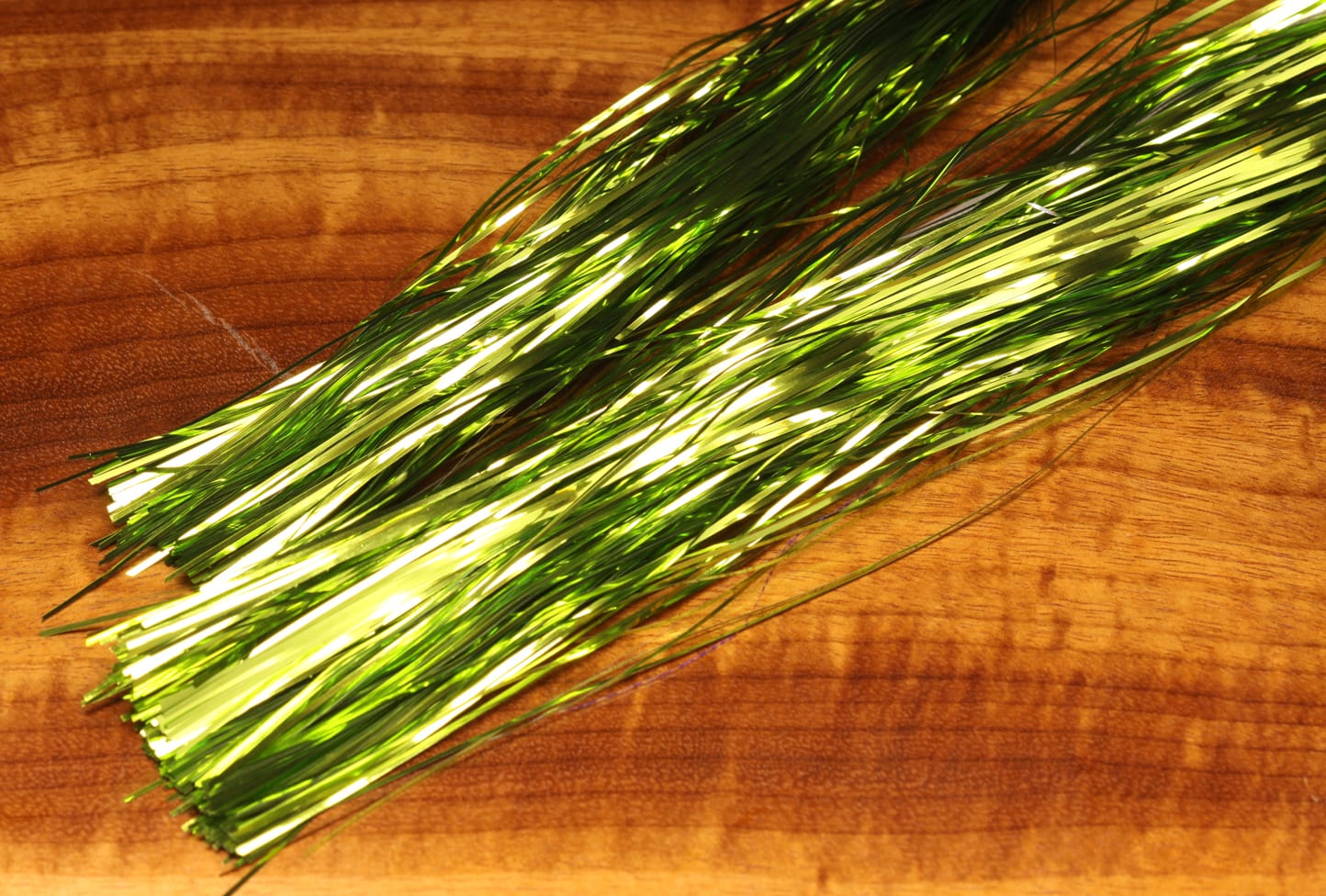 Hedron Magnum Flashabou metallic chartreuse green tinsel strands for fly tying on wood background