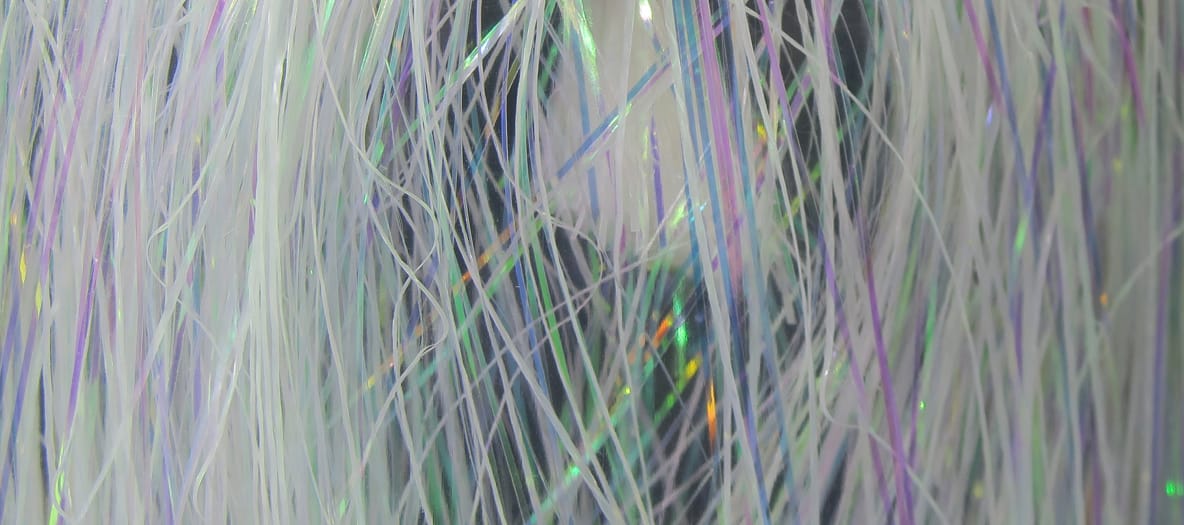 Pearl white Hedron Flashabou strands with iridescent green and purple flashes, thin synthetic tinsel for fly tying