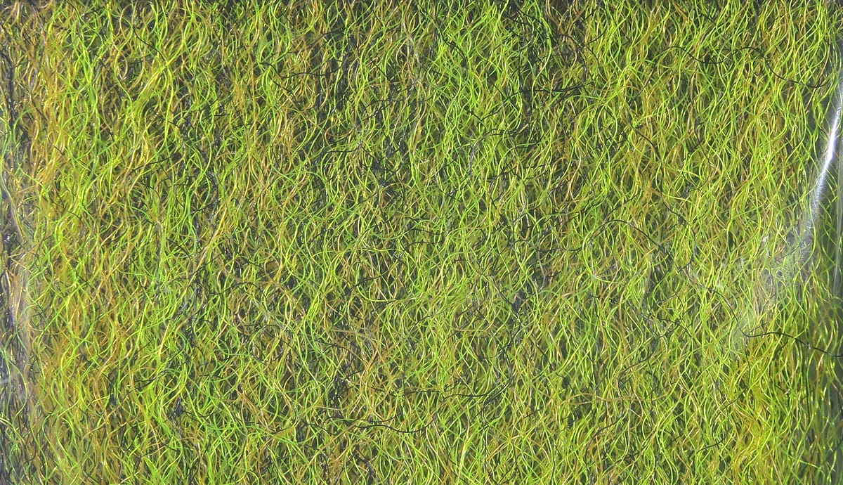 Hedron fuzzy fiber in chartreuse and olive with black accents, tangled strung synthetic strands for fly tying