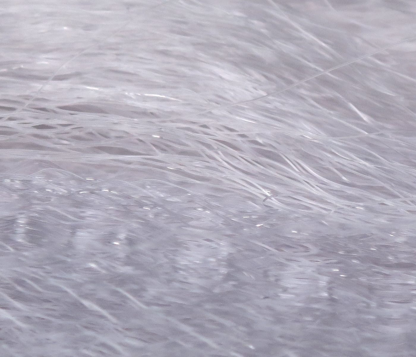 Pale silver-white Hedron Supreme Super Hair: fine translucent synthetic fibers with glossy, wispy texture for fly tying.