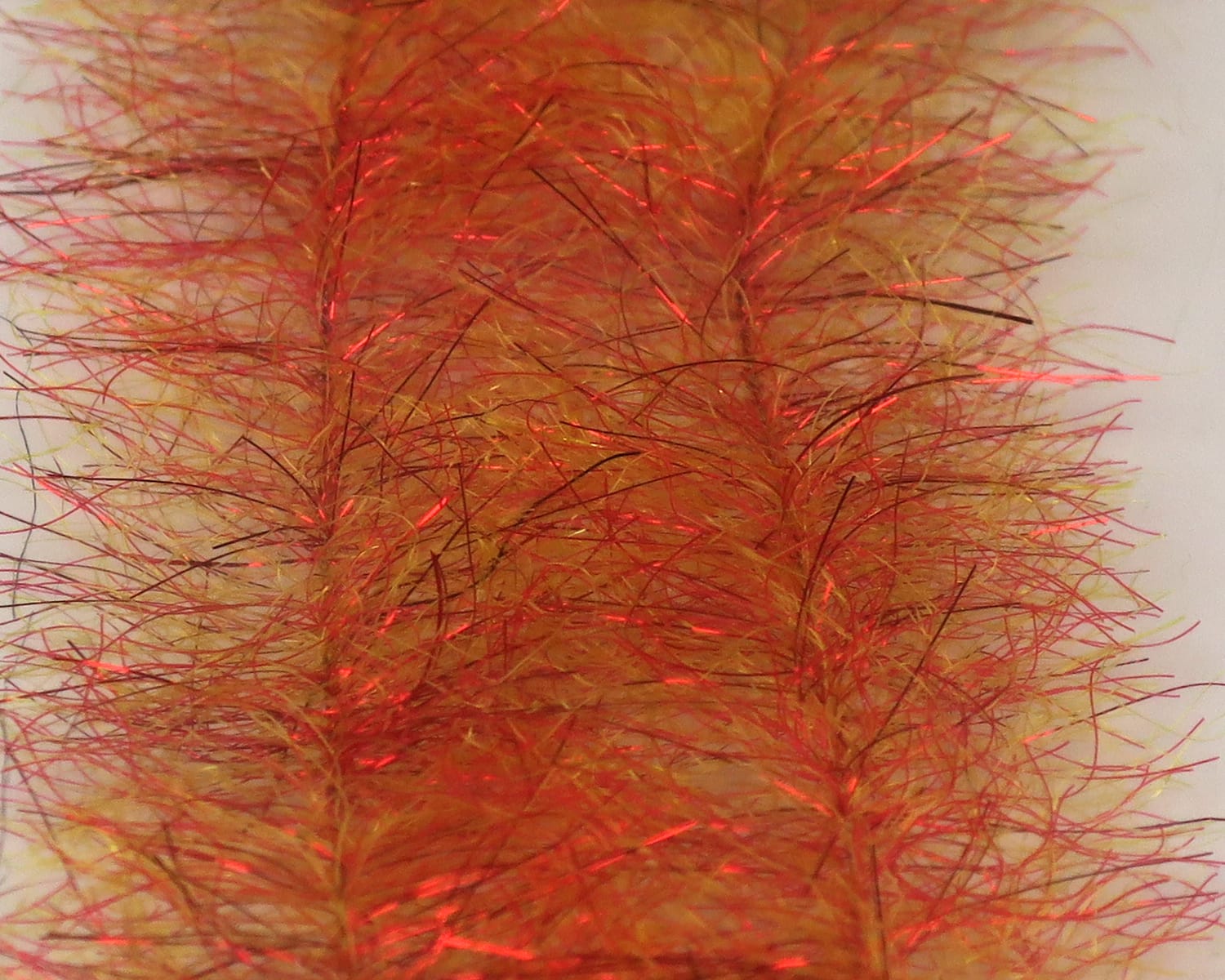 Orange-gold synthetic baitfish brush with red iridescent flash fibers, fluffy streamer material for fly tying