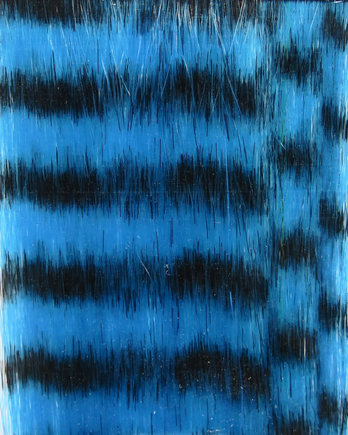 Blue and black barred grizzly fibre with glossy synthetic hairs for fly tying