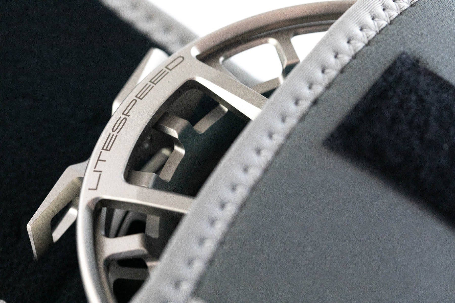 Silver machined aluminum Lamson Litespeed fly reel with ported spool, engraved LITESPEED and gray stitched neoprene cover