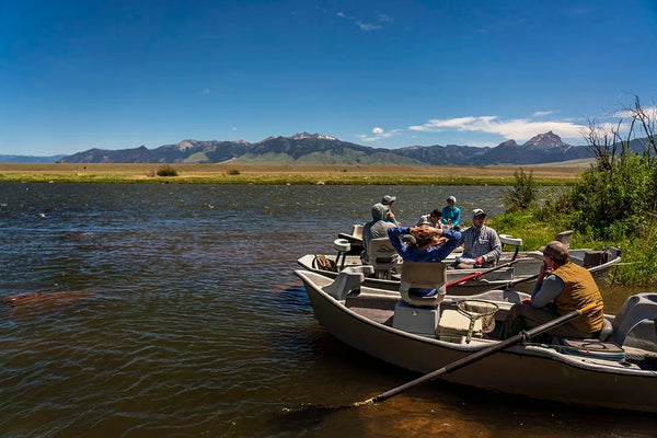 Trident Madison Double R aluminum fishing boat with group of anglers on mountain lake, scenic valley backdrop