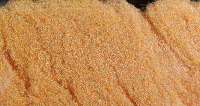 McFlyFoam orange synthetic fly tying yarn close-up showing shiny fuzzy foam fibers with peach-orange fluffy texture