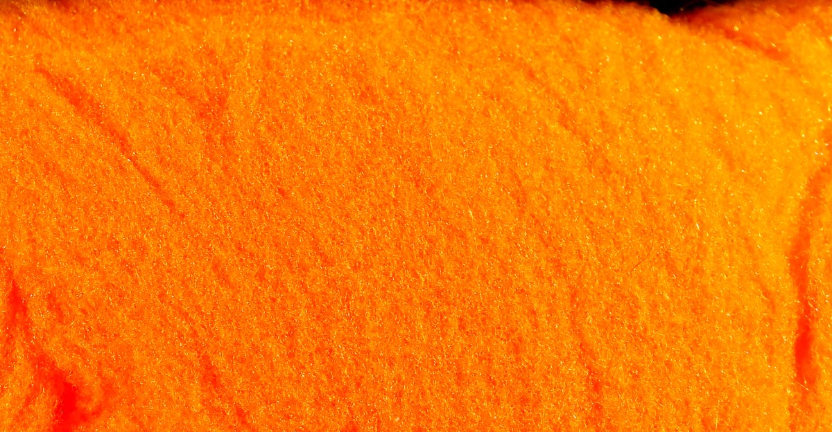 Bright fluorescent orange McFlyFoam fly tying yarn close-up showing soft textured synthetic foam fibers with subtle sparkle