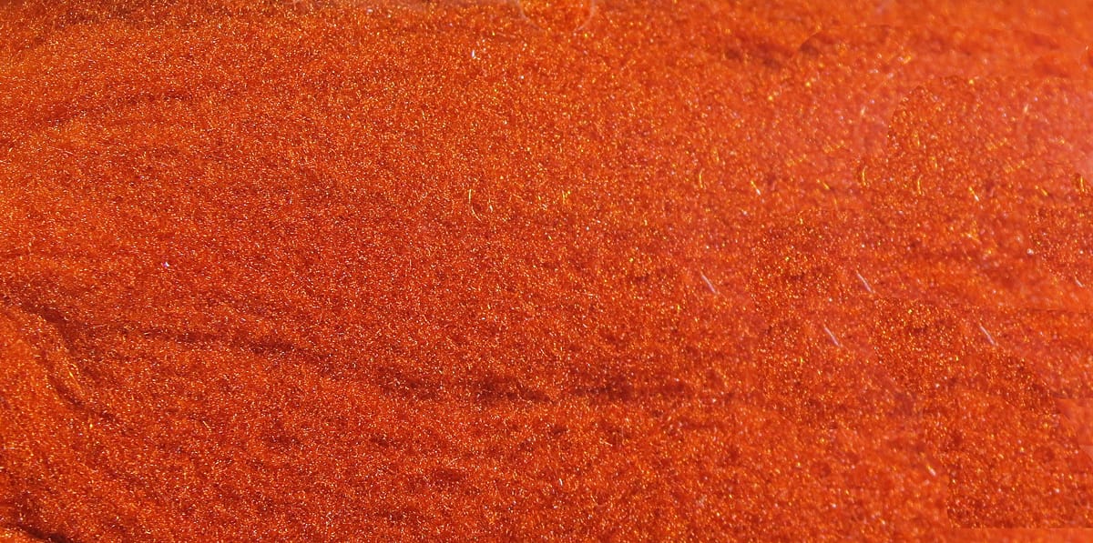 Bright orange McFlyFoam fly tying yarn, close-up of soft foam fibers with fine gold sparkle and shimmering texture