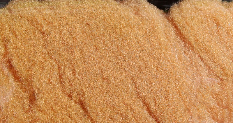 McFlyFoam orange synthetic fly tying yarn close-up showing shiny fuzzy foam fibers with peach-orange fluffy texture