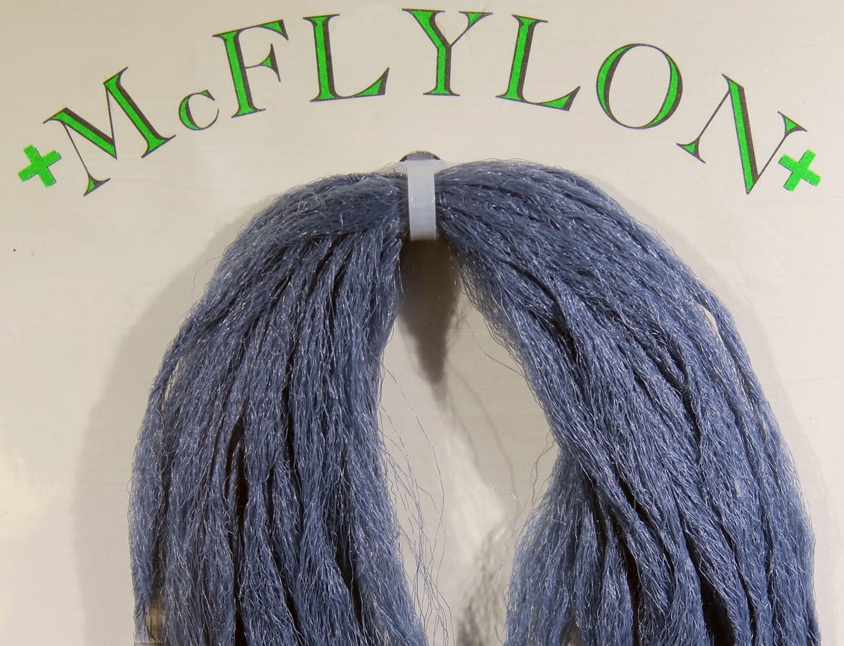 Steel-blue PolyPro McFlylon synthetic strands for fly tying, shimmering textured fibers bundled with white plastic clip