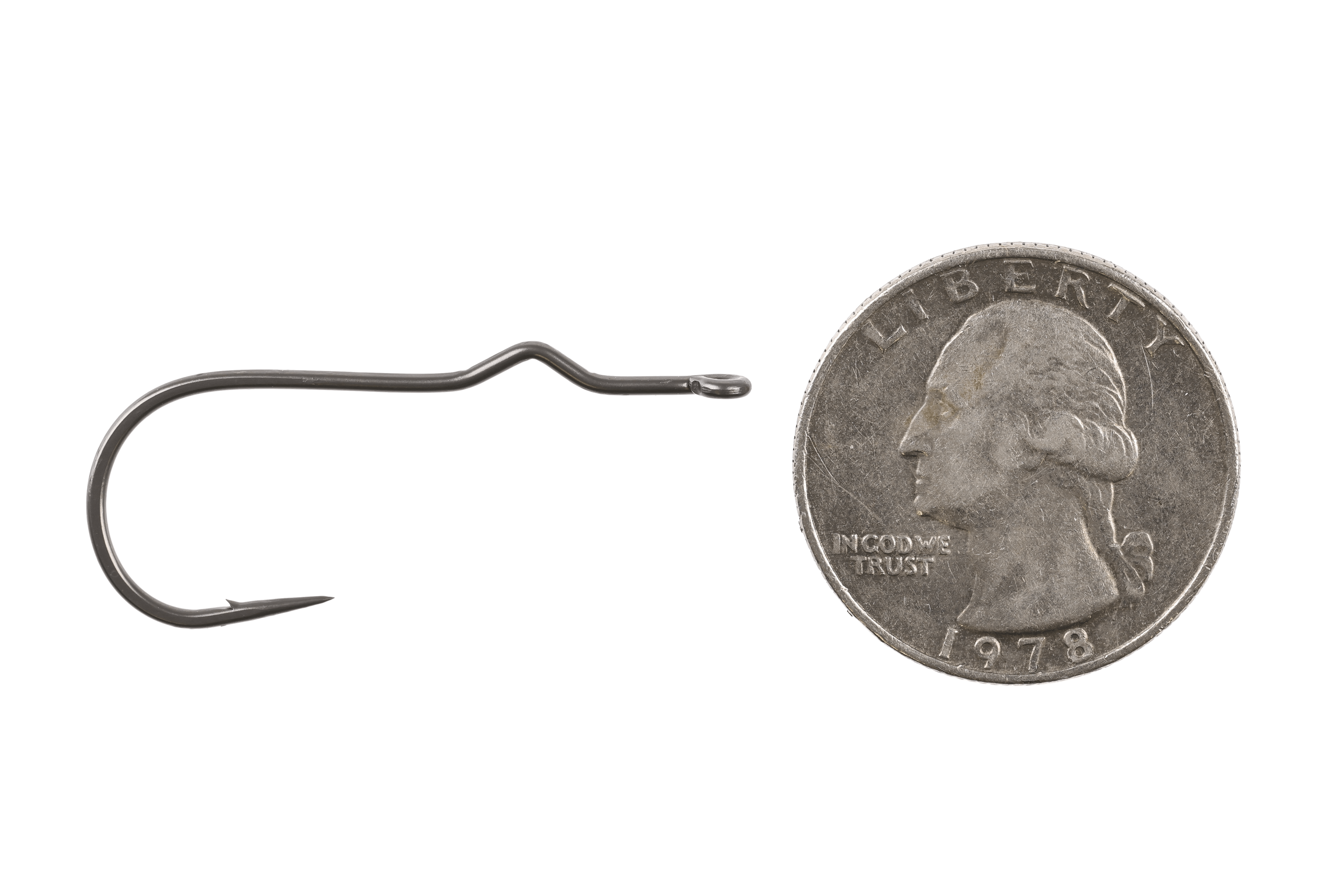 Matte gunmetal kinked popper hook with turned eye and sharp point beside a US quarter for scale, fly tying hook