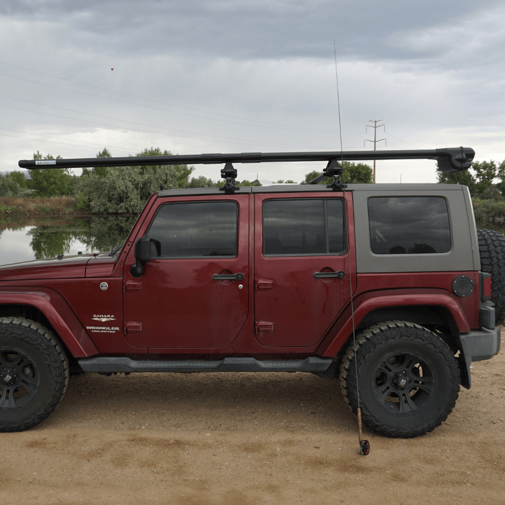 Red Jeep Wrangler with black roof rack and River Quiver Extension Kit mounted on top near water