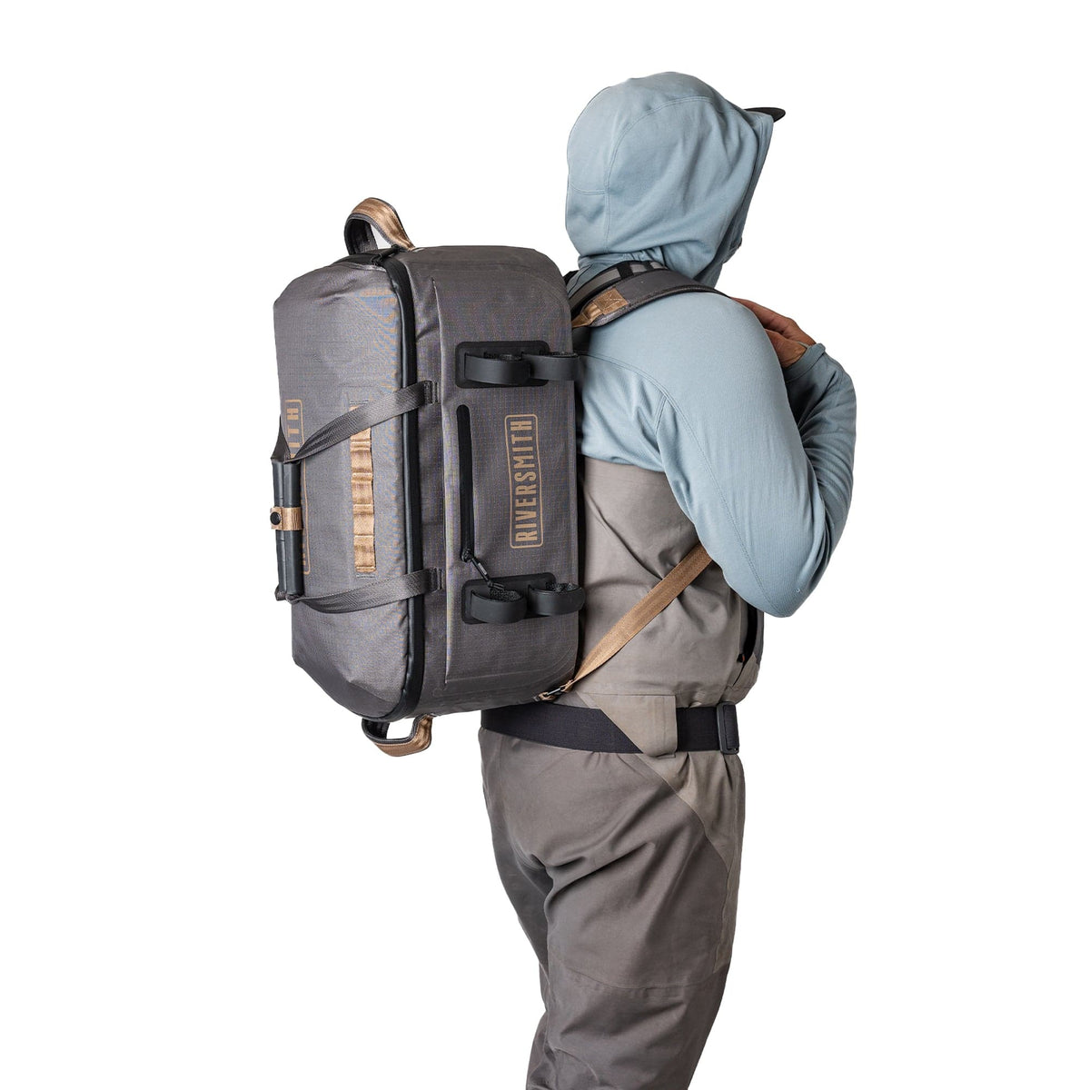 Riversmith waterproof duffel bag in gray and tan worn on hiker's back with hood up