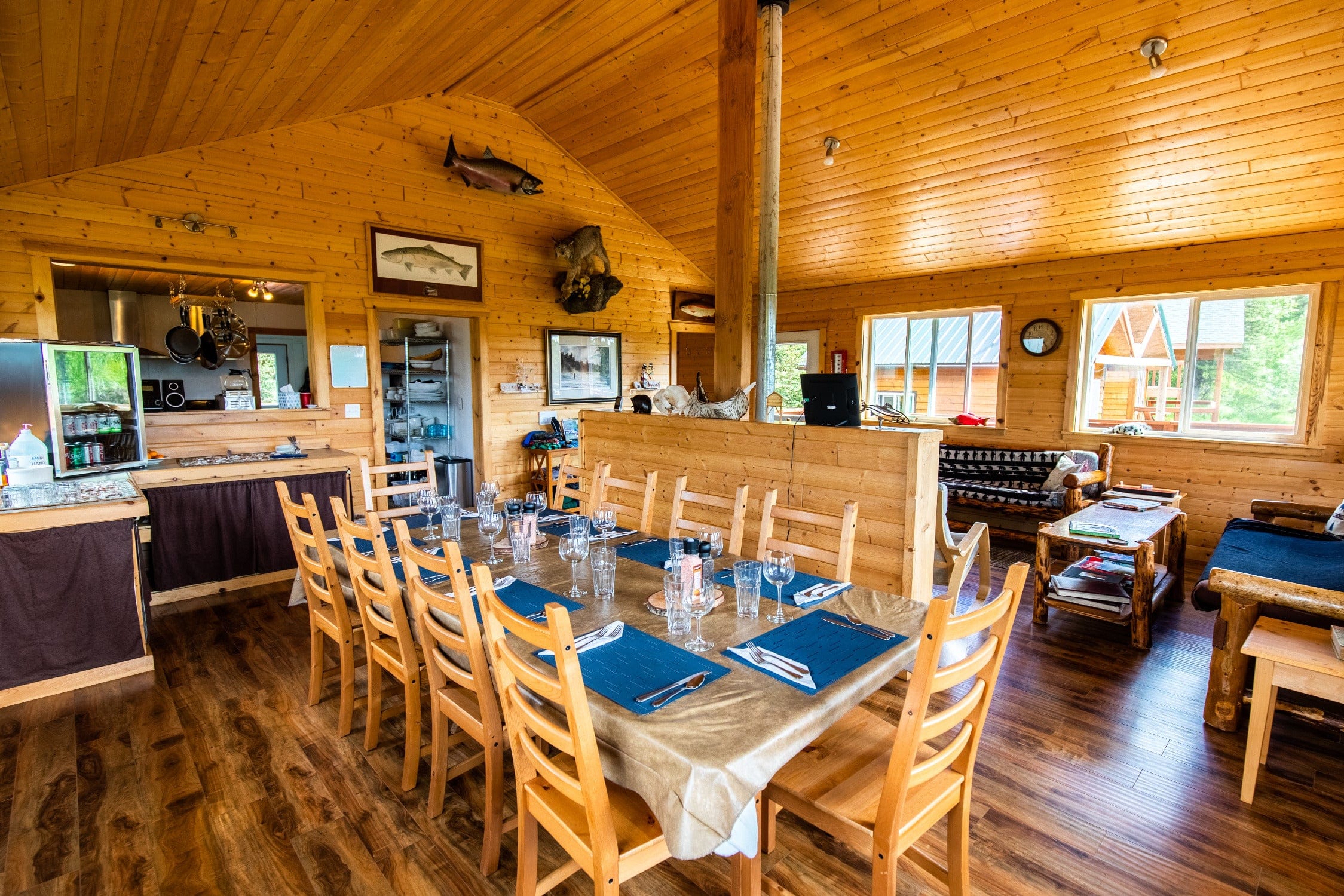 Rustic Copper River lodge dining room with long wooden table, chairs, blue placemats and polished wood walls