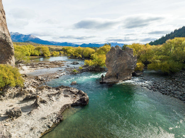 Turquoise mountain river with gray rock formations and golden willow trees beneath cloudy skies at Arroyo Verde