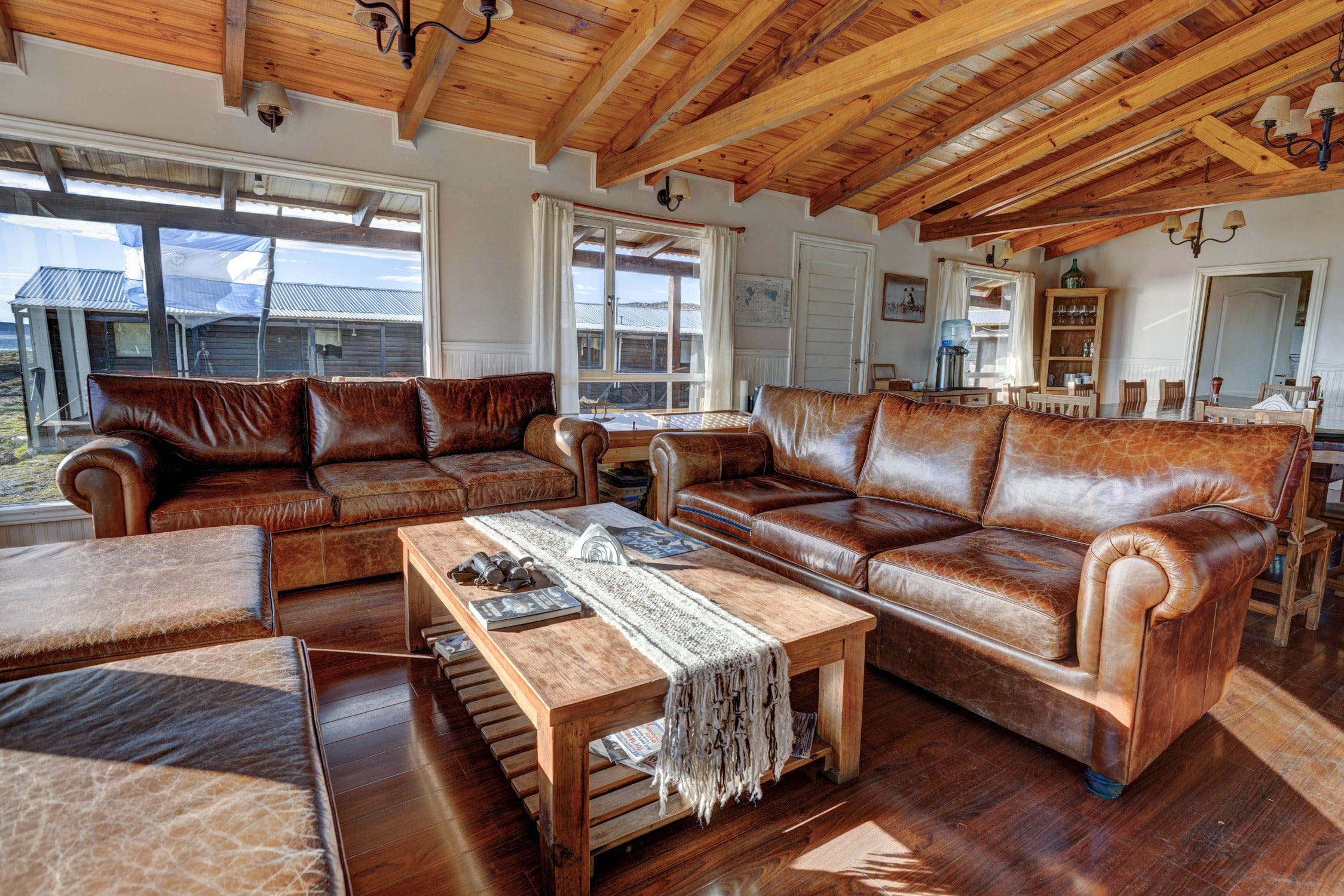 Rustic living room at Jurassic Lake Lodge with brown leather sofas, wooden coffee table and exposed pine beams