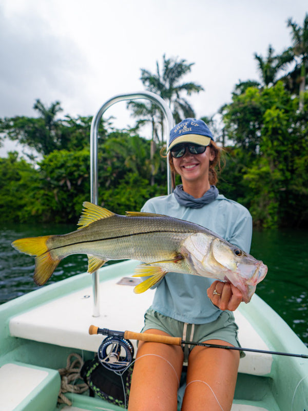 Woman holding large yellow-fin fish on boat at Belize River Lodge, fly fishing adventure