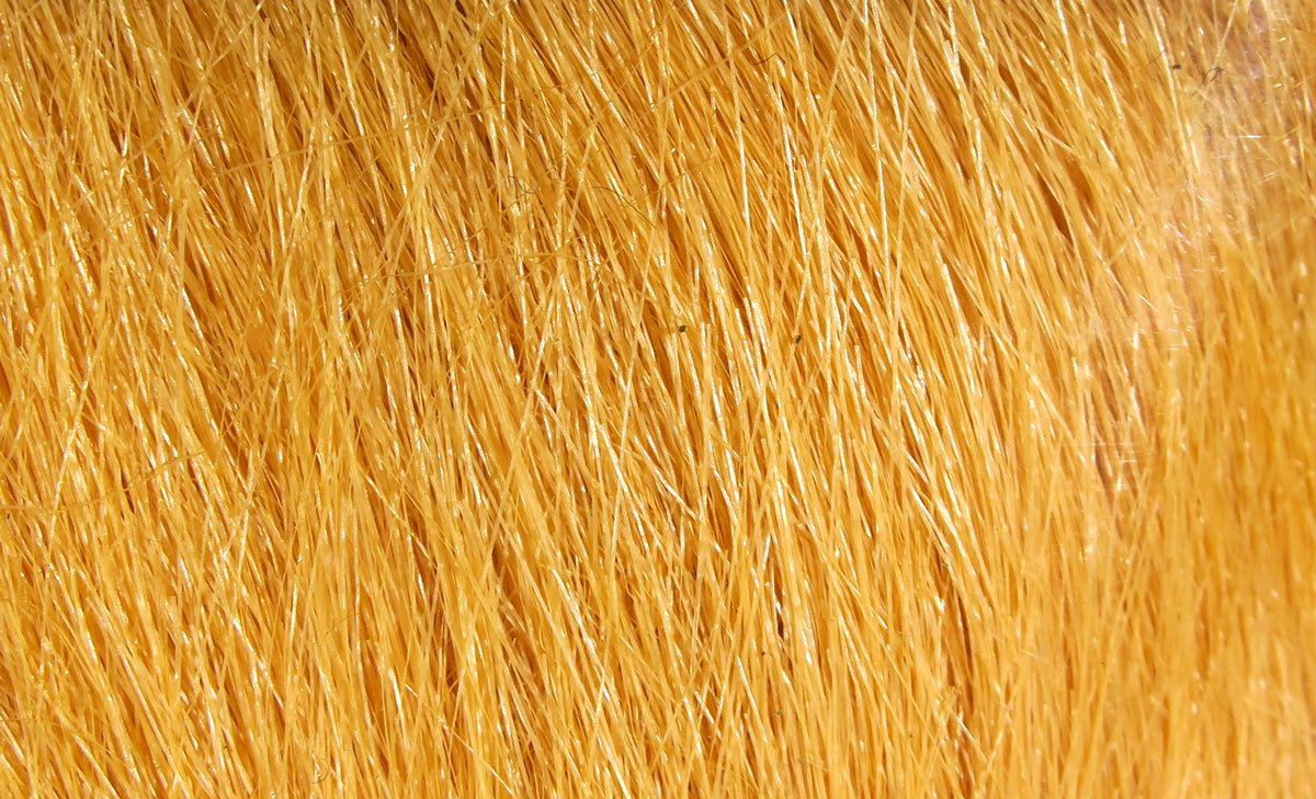Golden-orange Hareline craft fur close-up showing long glossy fibers for fly tying
